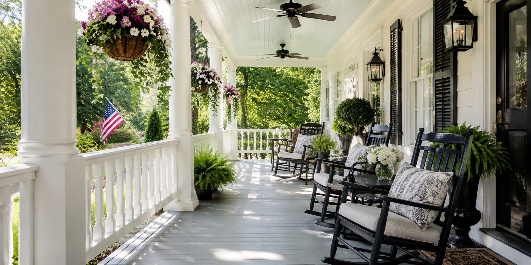 A classic Southern veranda with white columns, rocking chairs, hanging flower baskets, and ceiling fans. Breezy daylight ambiance.